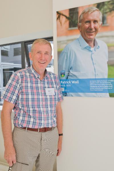 Patrick Wall standing beside his Alumni Wall photo