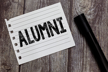 Image of the word Alumni written on a page torn out of a notebook