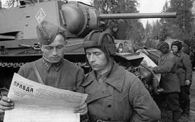 2 soldiers looking at a map with tank behind